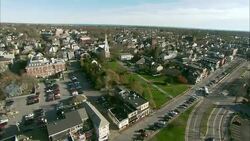 An aerial view shows town buildings close to highways and the sea. Stock Footage