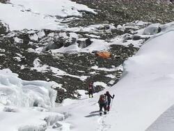 MS PAN Shot of three people with climbing eqipment walking in ice and snow on glacier with reaching basecamp at himalaya / Mt. Everest, Nepal Stock Footage