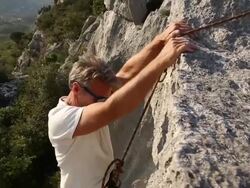 Man climbs vertical rock cliff Stock Footage