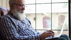 Adult senior bearded man sitting with a laptop Stock Footage