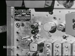 1951: EMERGENCY PREPAREDNESS: DRAMATIZATION: Men working Radio Communications room. CU Male hand adjusting knob on General Electric (GE) radio plate, MS Checking transmission. 'Colonel' walking through room.  Civil Defense Plan, Red Scare, McCarthyism Instructional Video