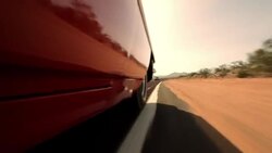 A red convertible swerves near the solid white line on the shoulder of a desert highway. Stock Footage