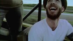 Film footage of road trip, driver looks up at friend standing in backseat with American flag waving out of classic Bronco Stock Footage