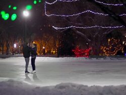 Couple skates together on a snowy winter evening. Stock Footage