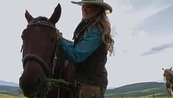 Female rancher petting and feeding horse in rural field Stock Footage