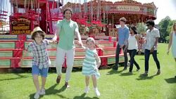 Children dragging father at amusement park Stock Footage