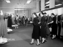 1950: DENVER, COLORADO: FASHION: POV Car driving up to downtown department store curbside. INT Women's department w/ women shopping, saleswomen helping. Upper class women sitting on couch while model models suit for them, upscale. Instructional Video