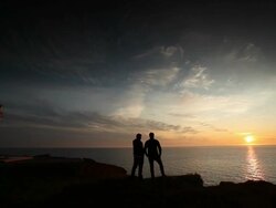People look at the sunset near a lighthouse Stock Footage
