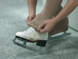 A female figure skater lacing up skates Stock Footage