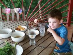 A young boy with chocolate on his face and arm sits at table eating from a big bowl lined with chocolate creating his own concoction of chocolate milk. Stock Footage