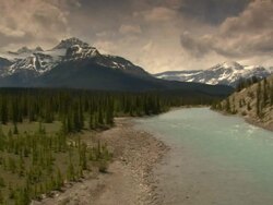 Long Shot static-A blue river flows past rocky shores and evergreen forests. / Canada Stock Footage