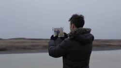 Young man looking at video on tablet on frozen pond in winter in rural Montana, USA. Stock Footage