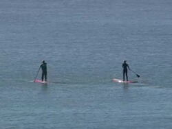 MS AERIAL Shot of man and woman moving in sea on surfing board Stock Footage