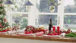 Christmas dinner placesettings, decorations and Christmas crackers on table near Christmas tree Stock Footage