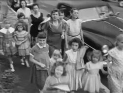 B/W 1950s high angle PAN pro-segregation women protestors walking with children on sidewalk / newsreel Stock Footage
