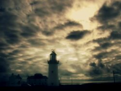 Lighthouse set against moody time lapse sky Stock Footage