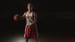 A confident basketball player dribbles a ball at center court of a gymnasium. Stock Footage