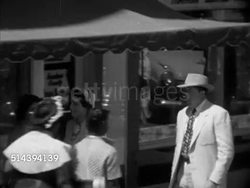 1953: CAMDEN, SOUTH CAROLINA: HA TD WS Business District w/ shops both side of street & cars angle parked at sidewalk. VS People walking sidewalk, children in ticket line at movie theater, Saturday matinee movie poster 'The Blazing Forest' behind children Instructional Video