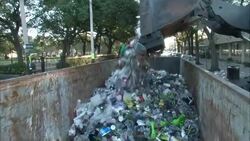 A front loader deposits trash into a dumpster. Stock Footage