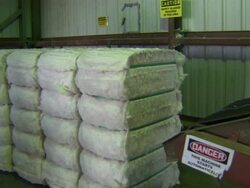 Machine sets down a large stack of cotton and then moves it along a conveyor belt with other stacks. Stock Footage