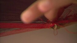 A woman weaves silk threads on a loom. Stock Footage