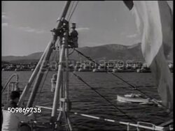 1940: FRENCH VICHY GOVERNMENT: WS Harbor w/ docked boats. French sailors walking w/ duffle bags. French Admiral Emmanuel Ollive leaning over table. HA WS French Cruiser ships in line. Instructional Video