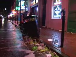 Medium Shot Tracking - Trash truck drives down a trash filled Bourbon Street / New Orleans Louisiana Stock Footage