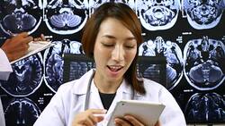 Female doctor on video call from her Office with X-ray image of the brain computed tomography on Background Stock Footage