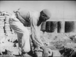 1952: ARAB DEVELOPMENT SOCIETY: WS Palestinian male refugees walking down dirt road w/ houses BG. MS Bilingual Arabic/English sign, VS Male construction workers building block & mortar house, Said Asfour SOT talking w/ tractor driver Hassan Abou Shab. Instructional Video