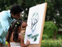 Man making a painting with his daughter on a easel  Stock Footage