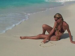 Blond girl drawing a heart on the beach Stock Footage