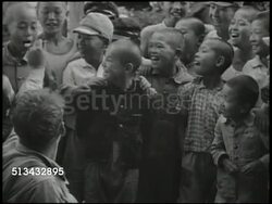 1946: OCCUPIED JAPAN: CHILDREN: VS Japanese children gathered around United States soldier, soldier spoon feeding boy, reading comics w/ another boy. Democratization Instructional Video