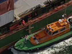 Medium shot pan pilot boat attached to moving container ship /zoom out aerial wide shot container ship / Cork Harbour, Ireland Stock Footage