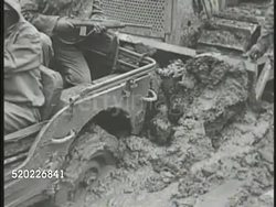 1945: OKINAWA, JAPAN: RAINY SEASON: US African-American soldier driving jeep in mud w/ bulldozer pushing behind. US Soldiers crossing swollen river. US Soldiers carrying supplies through mud plain. Pacific Theater, WWII, World War II. Instructional Video