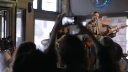 Man holding drink raises smartphone to snap photo of band at rock concert in Austin bar Stock Footage