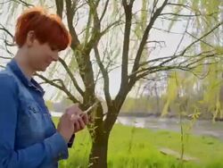 TS Joyful woman typing sms under the tree Stock Footage