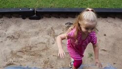 Young girl climbs up play-set and smiles with a sandbox underneath her Stock Footage