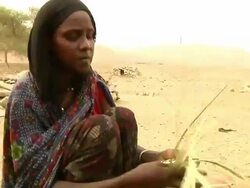 Woman braiding straw and small child next to her Stock Footage