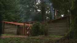 A man in pioneer clothing walks toward log cabins. Stock Footage