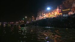 The moon shines over boats on a river as crowds bathe along the bank. Stock Footage