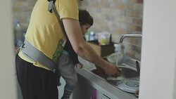 Father and son washing dishes in kitchen sink Stock Footage
