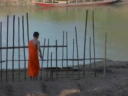 ZO Young monk building garden fence along Mekong River / Luang Prabang, Laos Stock Footage