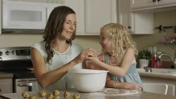 Medium panning shot of mother and daughter rolling cookie dough / Orem, Utah, United States Stock Footage