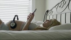 Medium shot of pregnant woman with headphones on belly / Cedar Hills, Utah, United States Stock Footage