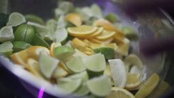 SLO MO CLOSE-UP SELECTIVE FOCUS Bartender throwing lime and lemon wedges into bowl Stock Footage