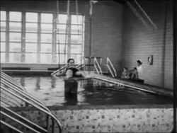B/W 1934 2 women pulling child with polio on platform into pool for water therapy / Indiana / newsreel Stock Footage