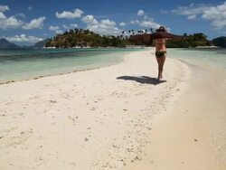 WS beautiful caucasian woman walks along idyllic sandbar with tropical island in background / Snake Island, Bacuit Archipelago, El Nido, Palawan, Philippines Stock Footage