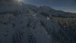 Evergreen trees grow on steep, snow-covered peaks. Stock Footage