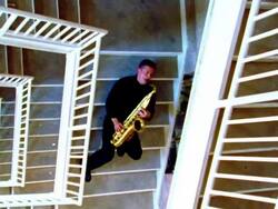 OVERHEAD man sitting on stairs playing saxophone Stock Footage
