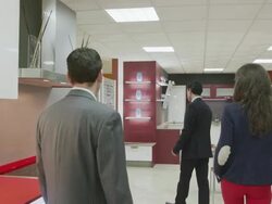 TS MS salesman showing kitchen furniture to young couple in kitchen showroom Stock Footage